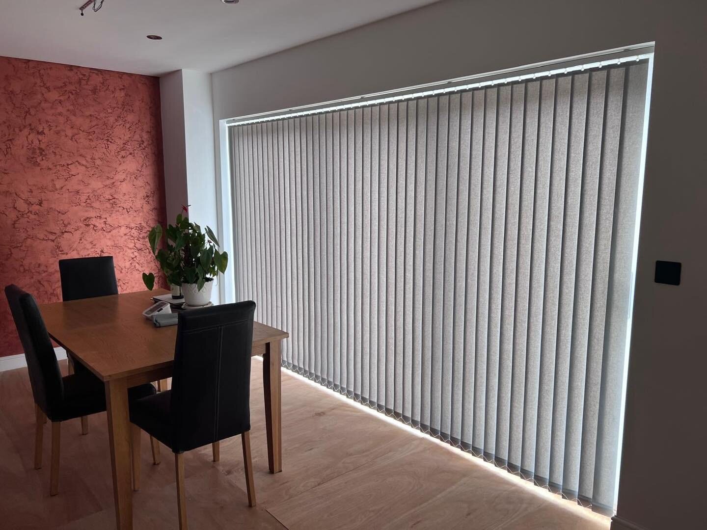 Grey vertical blinds fitted across a wide dining-room window